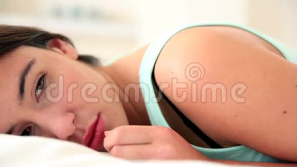 躺在床上看着摄像机的不开心的黑发女人视频的预览图