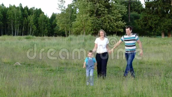 母亲父亲和儿子走在草地上视频的预览图