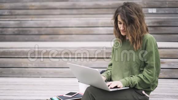 年轻女子在外面的笔记本电脑上打字视频的预览图