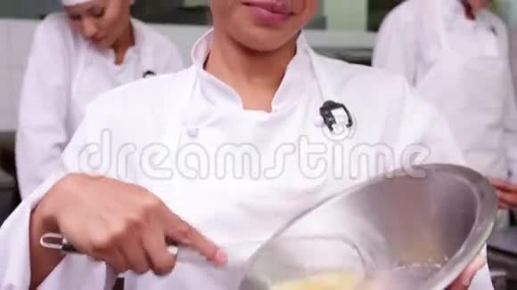 微笑的厨师在碗里搅拌鸡蛋视频的预览图