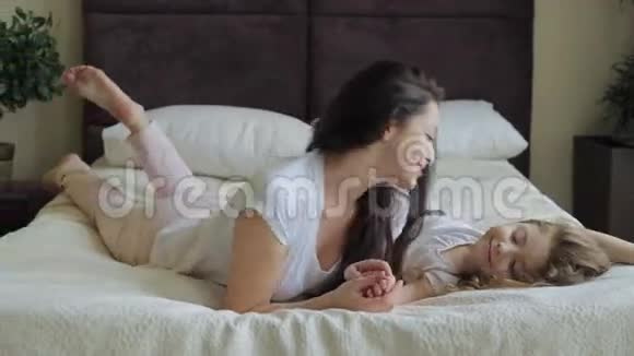 母亲和女儿躺在家里的床上玩耍视频的预览图