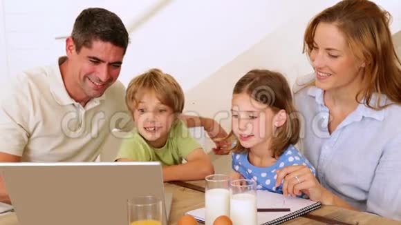 快乐的一家人一起在早餐桌上用笔记本电脑视频的预览图