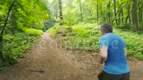 成年男子在森林小径上的森林大自然中慢跑享受它看上去很快乐视频的预览图