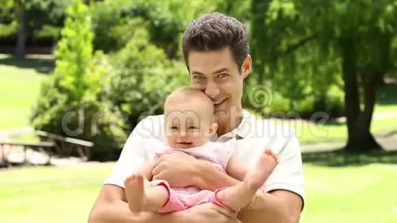 快乐的父亲抱着他的宝贝女儿在公园里视频的预览图