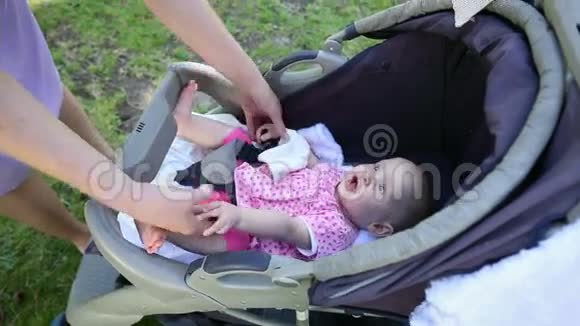 妈妈在公园里的婴儿车里照顾她的女婴视频的预览图