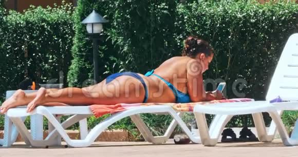 女人在泳池边的椅子上晒日光浴视频的预览图