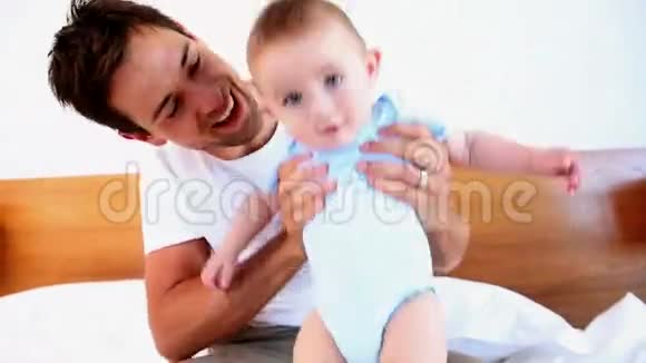 快乐的父亲和他的小儿子在床上玩耍视频的预览图