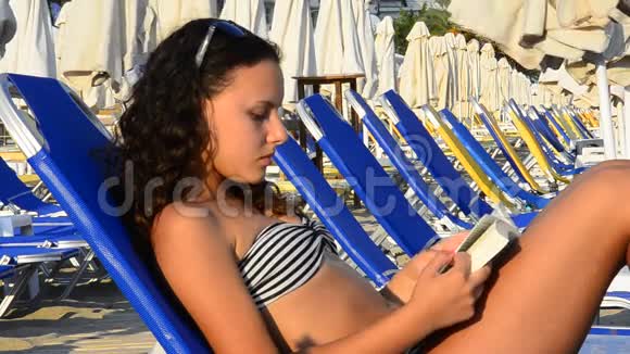 美丽的少女在海滩上看书视频的预览图