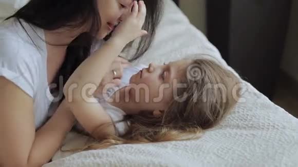 母亲和女儿躺在家里的床上玩耍视频的预览图