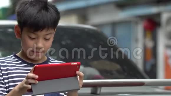 亚洲男孩在路边用智能手机视频的预览图