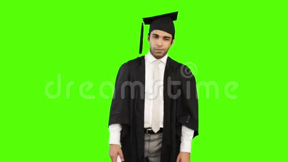 穿着毕业礼服拿着绿色背景文凭的男人视频的预览图