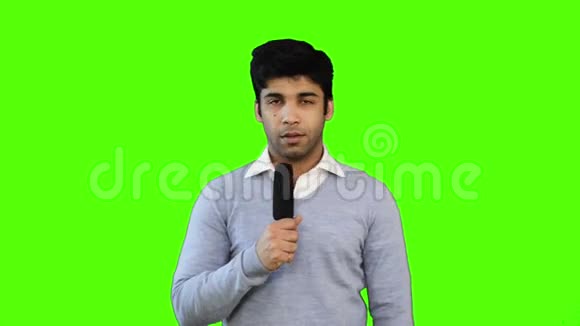 锁定镜头的男性电视记者谈话进入麦克风绿色背景视频的预览图