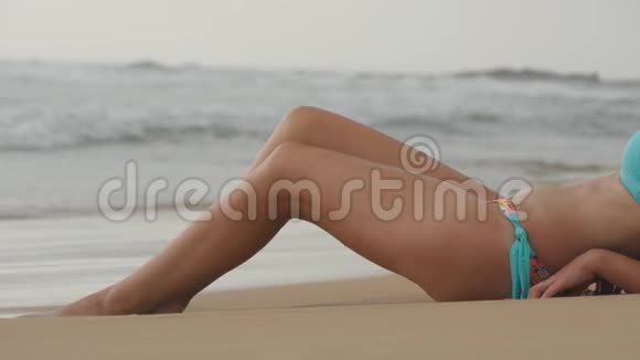 美丽的年轻女子躺在沙滩上的金色沙滩上在暑假旅行中放松关门视频的预览图