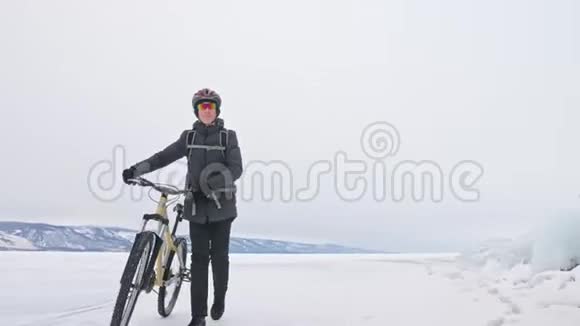 人在冰窟附近的自行车旁散步有冰洞和冰柱的岩石非常美丽骑自行车的是视频的预览图