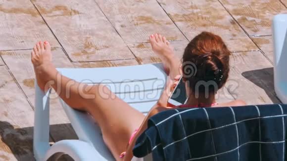 女人在泳池边的椅子上晒日光浴视频的预览图