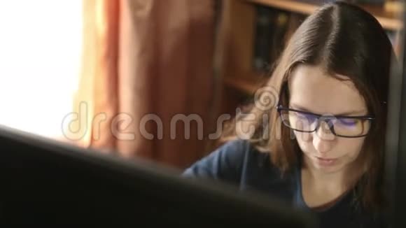 戴眼镜的年轻女孩坐在电脑前工作视频的预览图