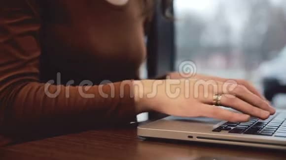 女人的手在咖啡座的笔记本电脑里工作视频的预览图