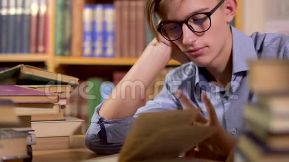 图书馆桌子上戴眼镜的年轻人视频的预览图
