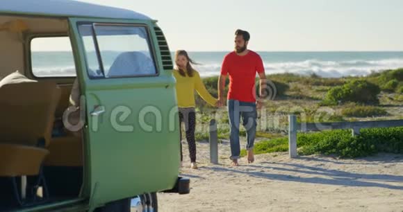 在阳光明媚的4k天气里年轻夫妇手牵手在海滩散步视频的预览图