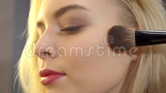 一个金发女孩在美容院接受化妆的镜头视频的预览图