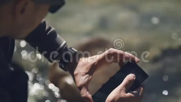 一个年轻人在他的智能手机上拍摄GornyAltai的本质慢动作视频的预览图