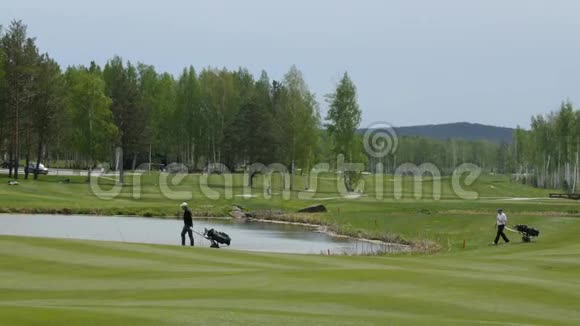 空中观景高尔夫球场高尔夫球手带着高尔夫球袋和手推车在球道上行走视频的预览图