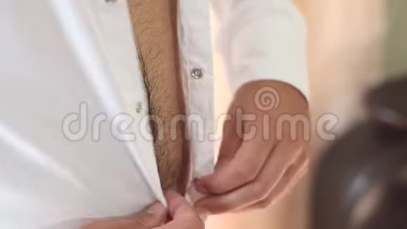 男人穿上白色衬衫男人把纽扣系在白色衬衫上视频的预览图