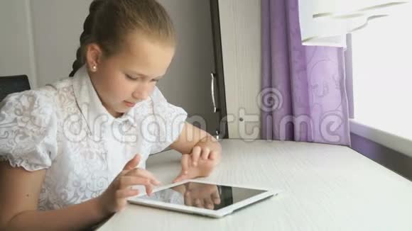 十几岁的女孩在桌子上用数码平板电脑视频的预览图