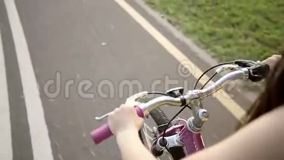 小女孩骑着粉红色的自行车在公园里骑自行车慢动作视频的预览图
