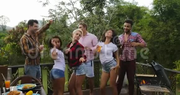 年轻人一边做饭一边跳舞快乐的团体在夏天的露台上聚会视频的预览图