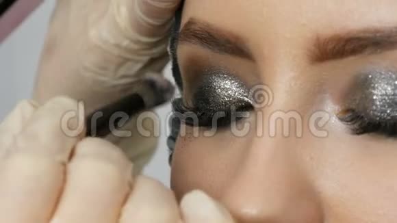 专业的高级时装化妆师用特殊的灰色眼影眼睛和眼睛制作出烟熏眼视频的预览图