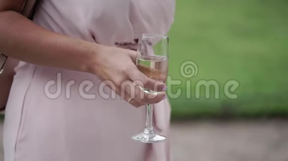 派对上穿着粉色连衣裙的女人喝着一杯起泡葡萄酒视频的预览图