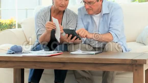 一对成熟夫妇正在计算他们的家庭账单视频的预览图