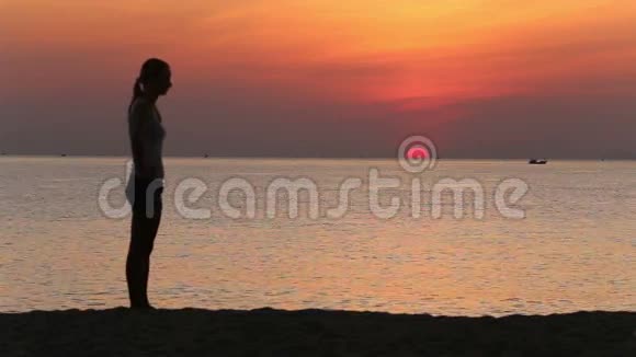 剪影女孩日出时在海滩上做运动视频的预览图