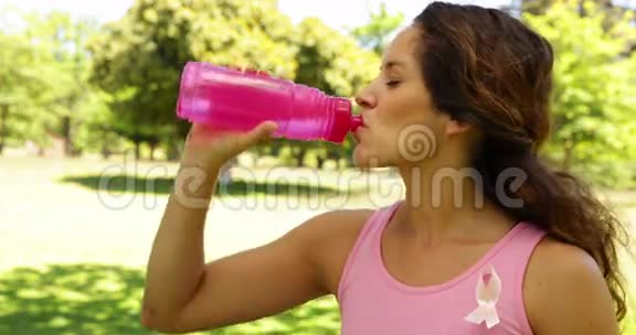 快乐的女人穿着粉红色的乳腺癌意识饮用水视频的预览图