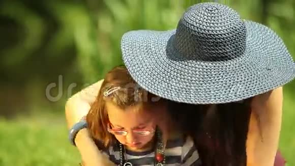 妈妈戴着草帽在公园里梳理女儿视频的预览图