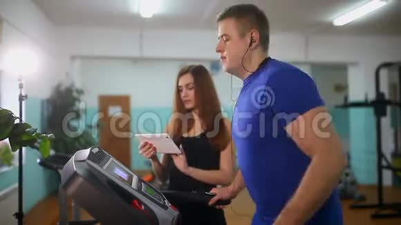 男子在跑步机上健身房女孩在跑步机教练运动健康的生活方式视频的预览图