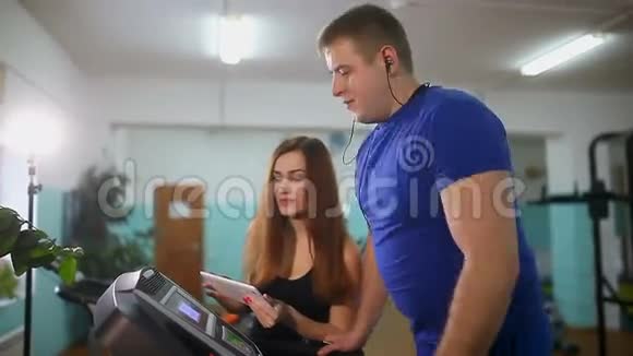 男子在跑步机上运动女孩在跑步机教练运动健康的生活方式视频的预览图