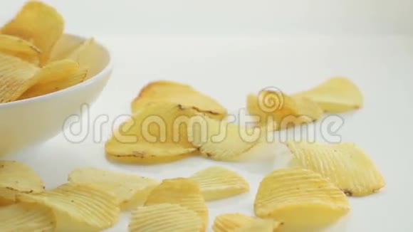 不健康的有害食物黄色美味的土豆肋脆片随机躺在碗和白色的桌子背景上近距离视频的预览图