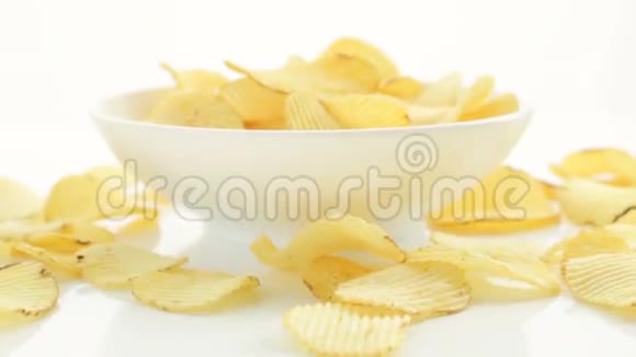 不健康的有害食物黄色美味的土豆肋脆片随机躺在碗和白色的桌子背景上近距离视频的预览图