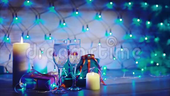 圣诞礼物蜡烛和两杯香槟蓝色花环背景视频的预览图