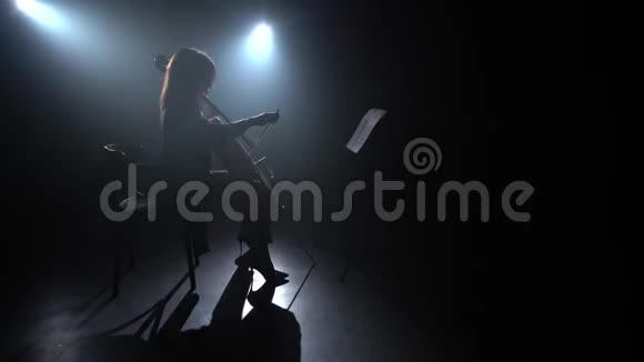 音乐家在黑暗工作室演奏大提琴剪影黑烟背景视频的预览图