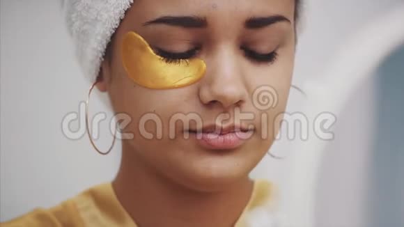 一幅美丽女人洗澡后用毛巾在头上的特写肖像将皱纹贴在眼睛下面视频的预览图