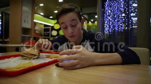 小男孩吃法国薯条写短信视频的预览图