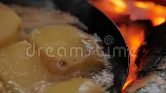 在露天篝火上用碳钢煎锅煎炸黄油土豆视频的预览图