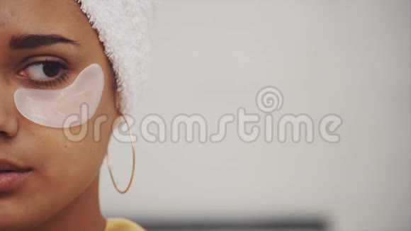 美丽女人沐浴后的特写肖像头上有毛巾眼睛下面有皱纹和深色的补丁视频的预览图