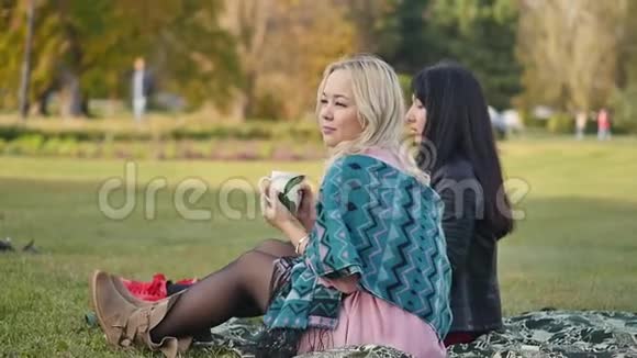 两个年轻的女人在城市公园玩得很开心日落时分在一个温暖的公园野餐的女朋友视频的预览图
