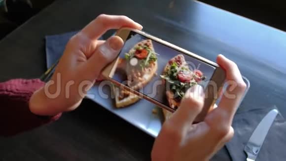 女手在餐厅用智能手机拍摄开胃的食物视频的预览图