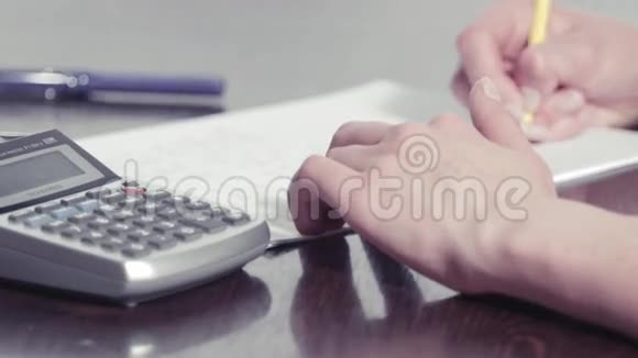 女人用铅笔写字用计算器打字视频的预览图