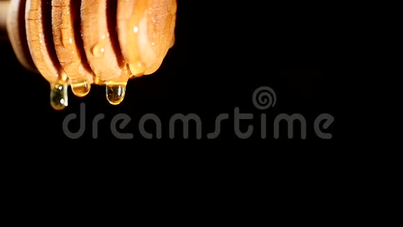 浓稠的蜂蜜从蜂蜜勺子里滴出来一滴在黑色的背景上合上视频的预览图